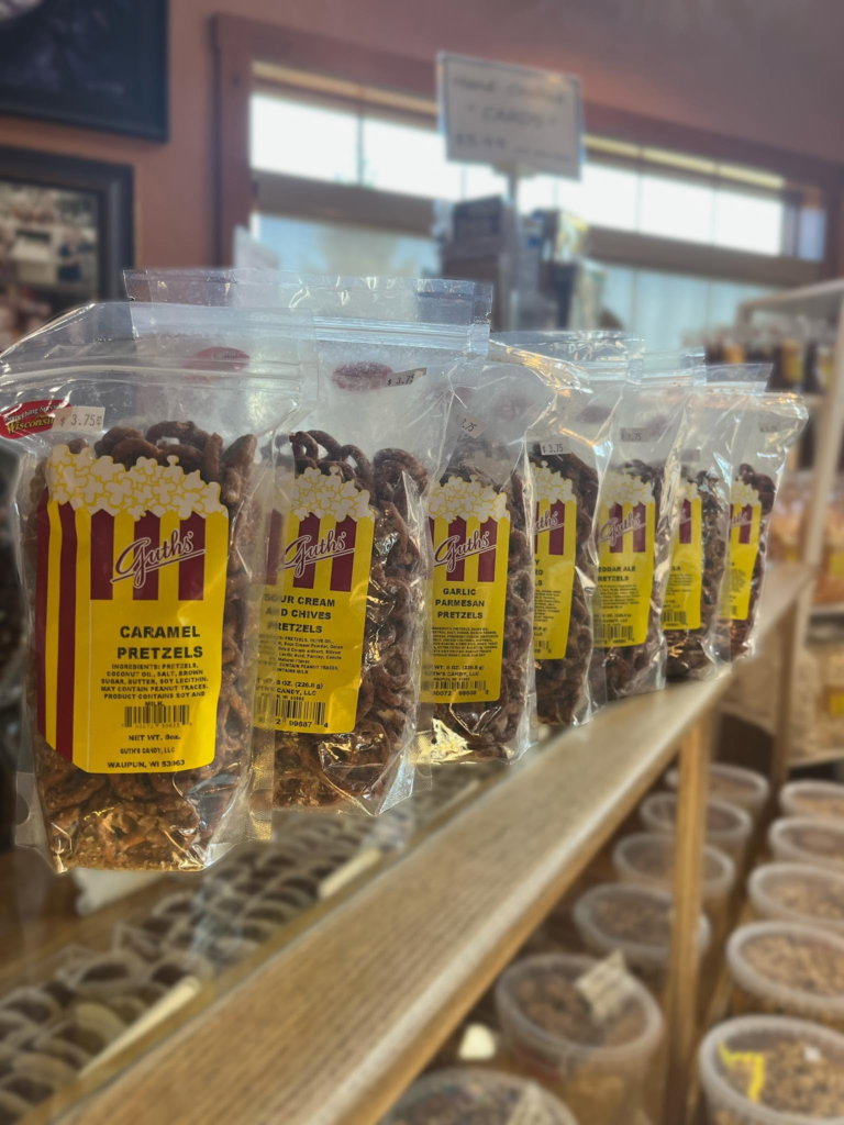 Bags of chocolate-covered pretzels and sweets on a shop shelf.