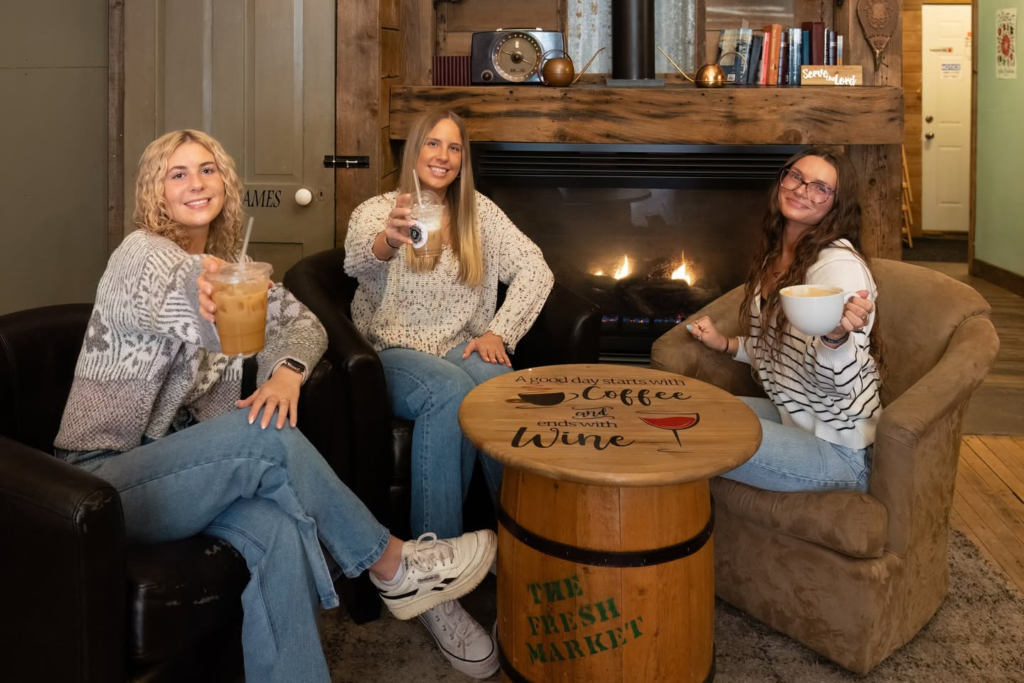 Friends relaxing by a fireplace with warm drinks.