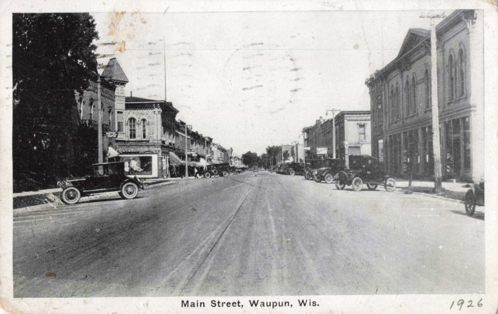 A vintage black and white postcard of Main Street in Waupun.