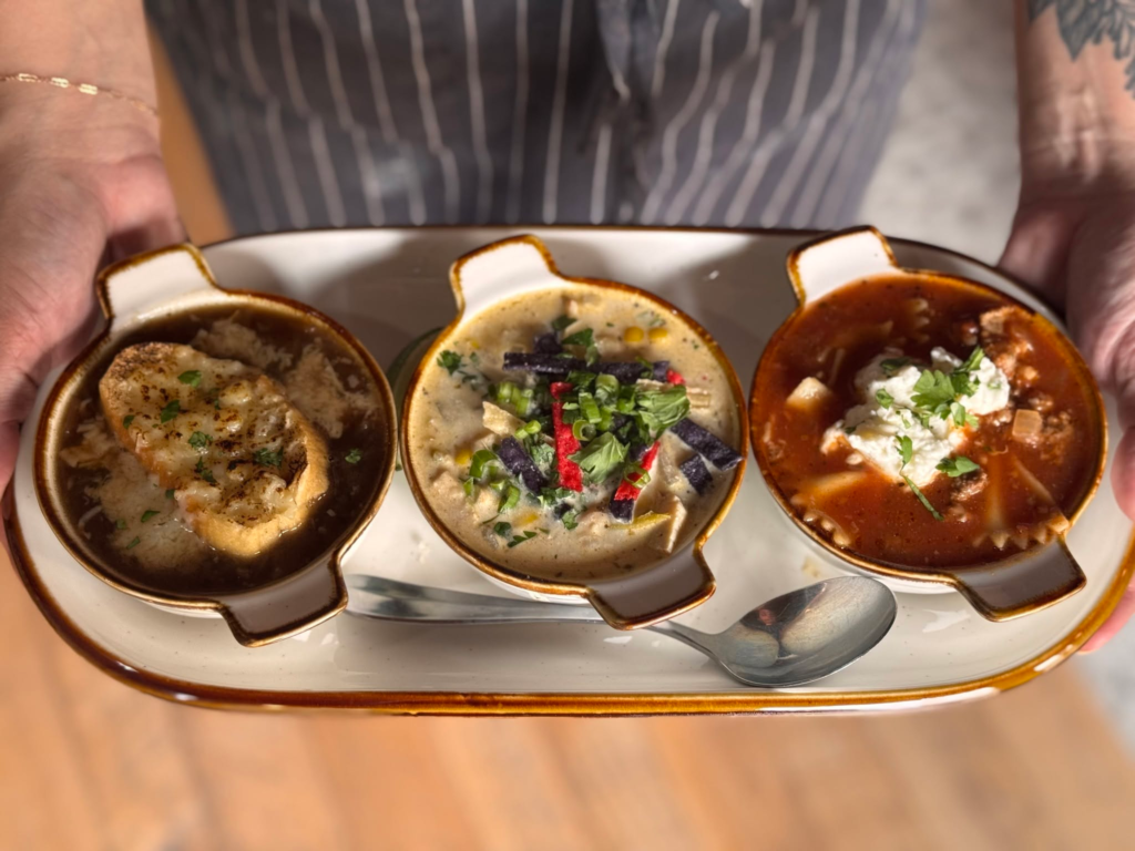 A trio of soups served in small crocks on a platter.