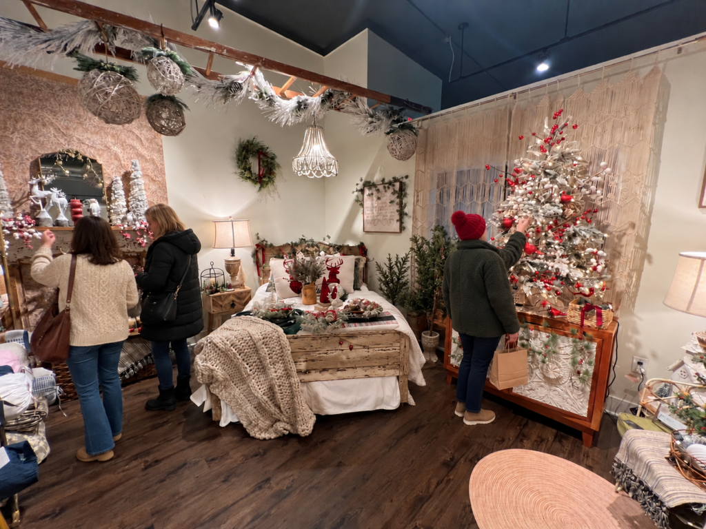 Holiday shoppers browsing a boutique decorated with a Christmas tree.