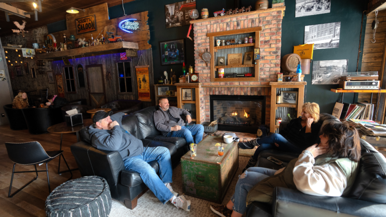 Friends relaxing by a stone fireplace in a cozy lounge.
