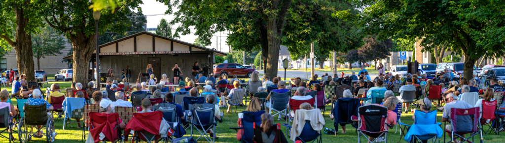 Families and neighbors relaxing on the lawn at Music in the Park in Waupun.