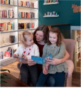 A mom and her girls reading books together.