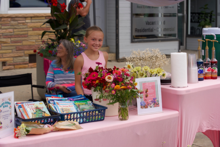 A young vendor selling flowers and crafts at the youth market.